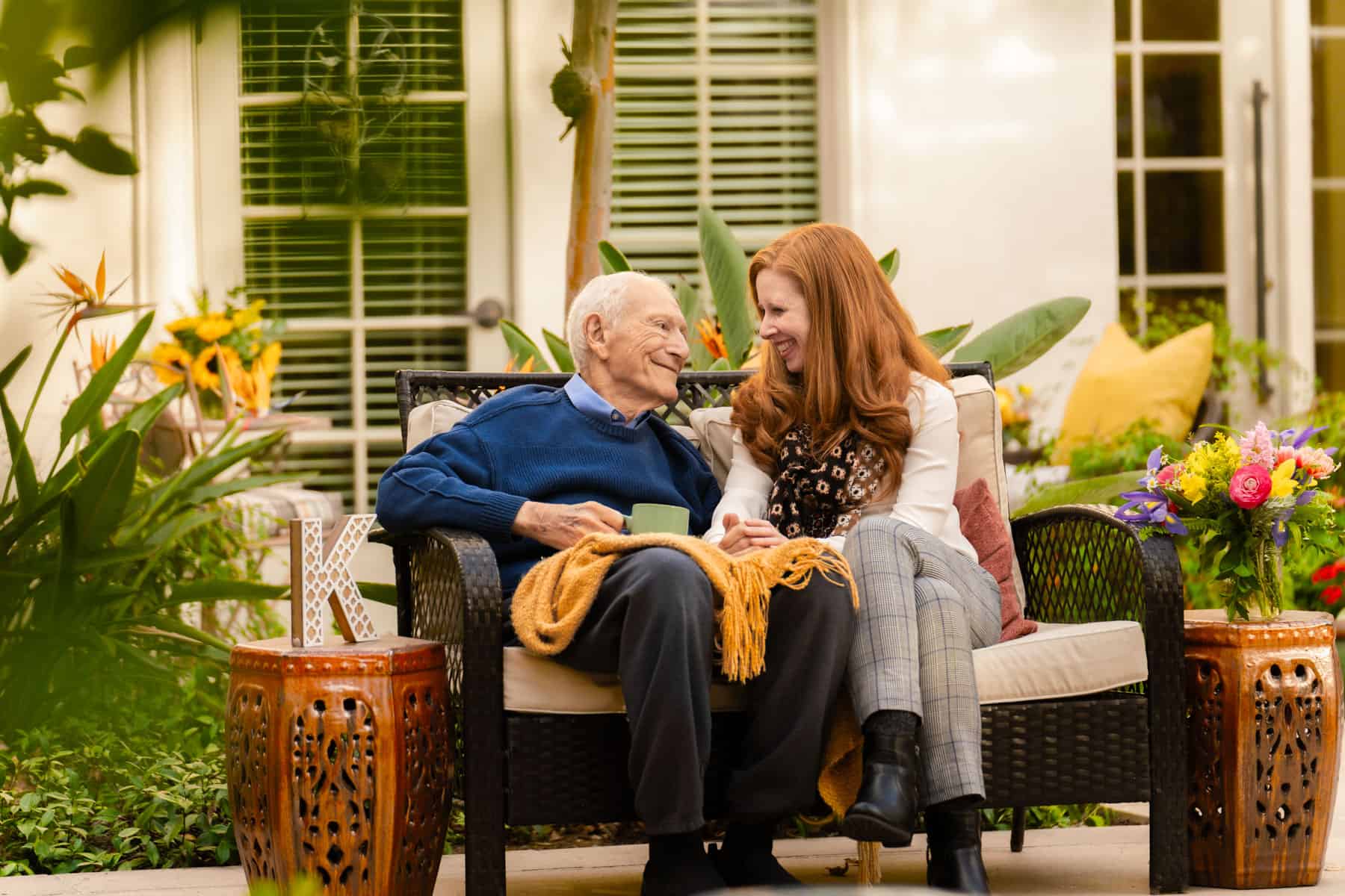 woman and elderly man smiling together on bench