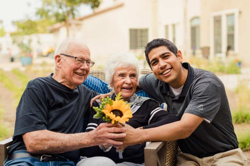 man with older couple holding sunflower