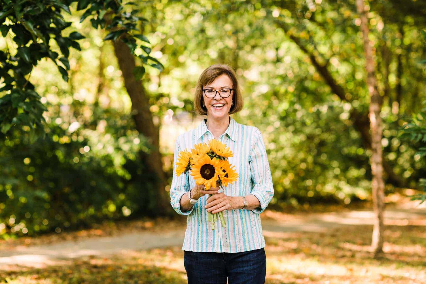 older lady holding sunflowers