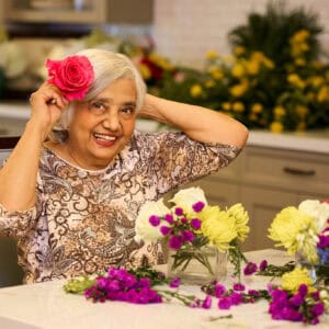 Senior lady holding a beautiful flower over her ear.