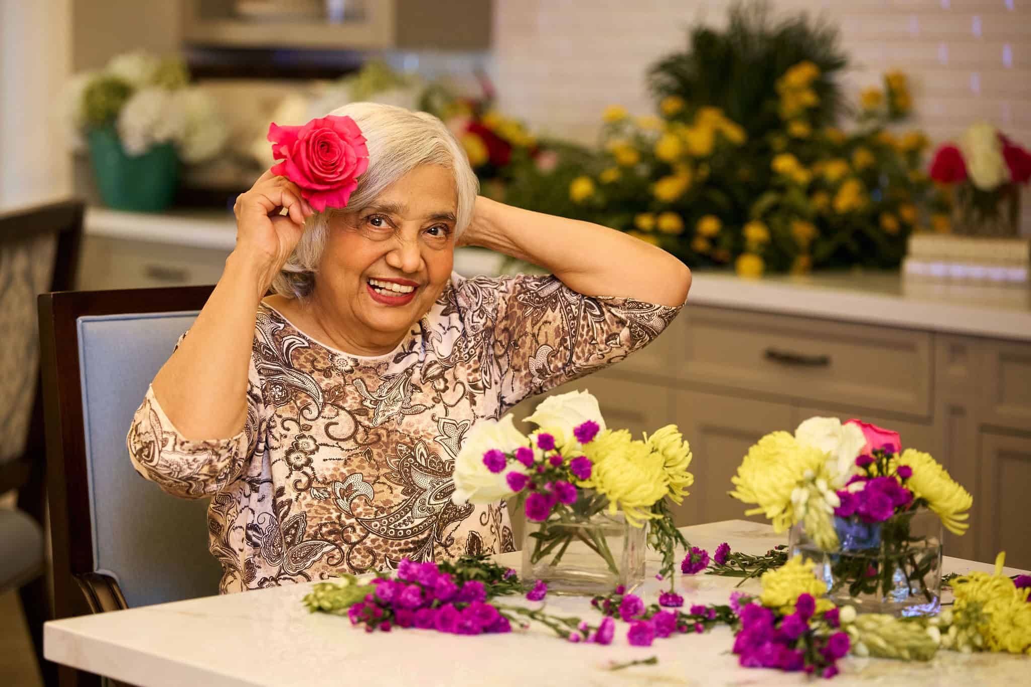 Senior lady holding a beautiful flower over her ear.